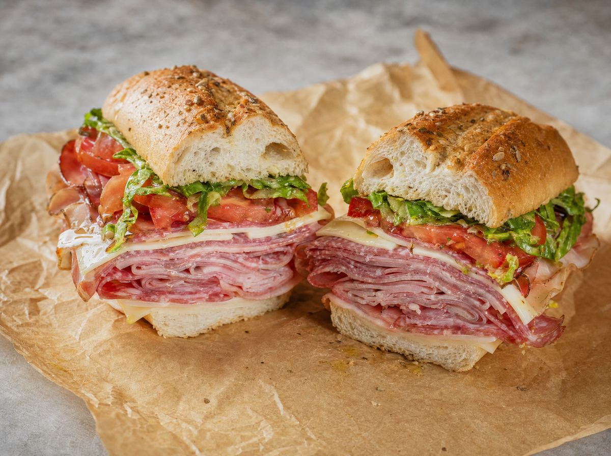 An Italian combo hero cut in half, layered high with cured meats, provolone and shredded lettuce